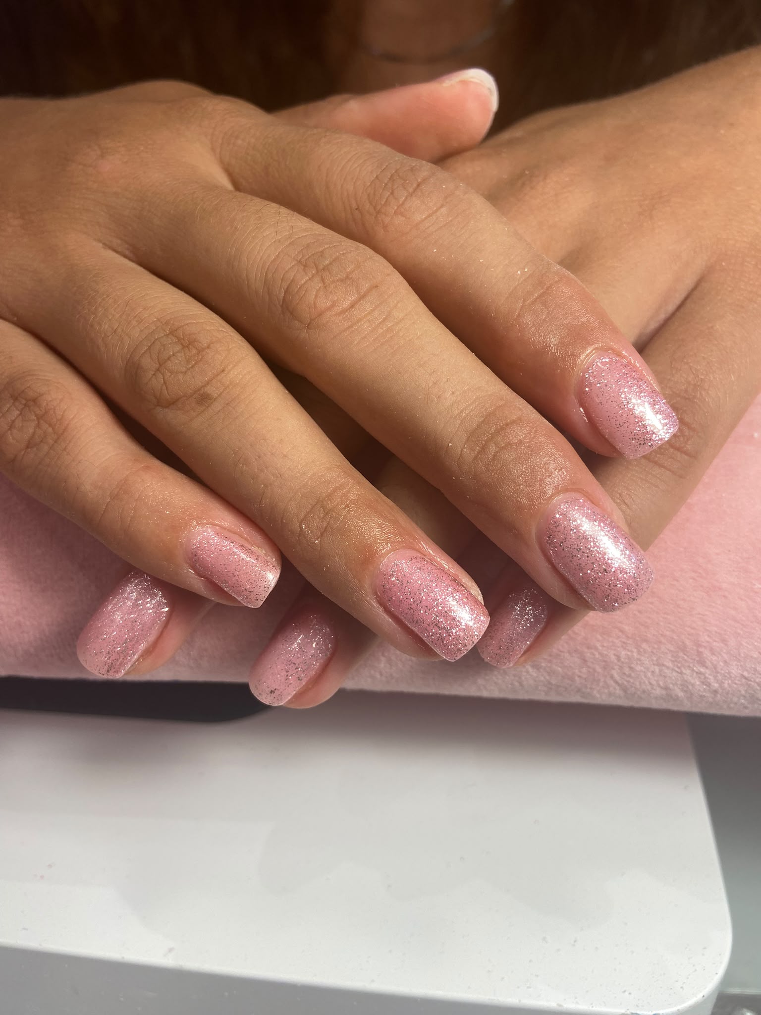 Unhas curtas quadradas em rosa com glitter prateado, feitas no Hit Nails Mafra