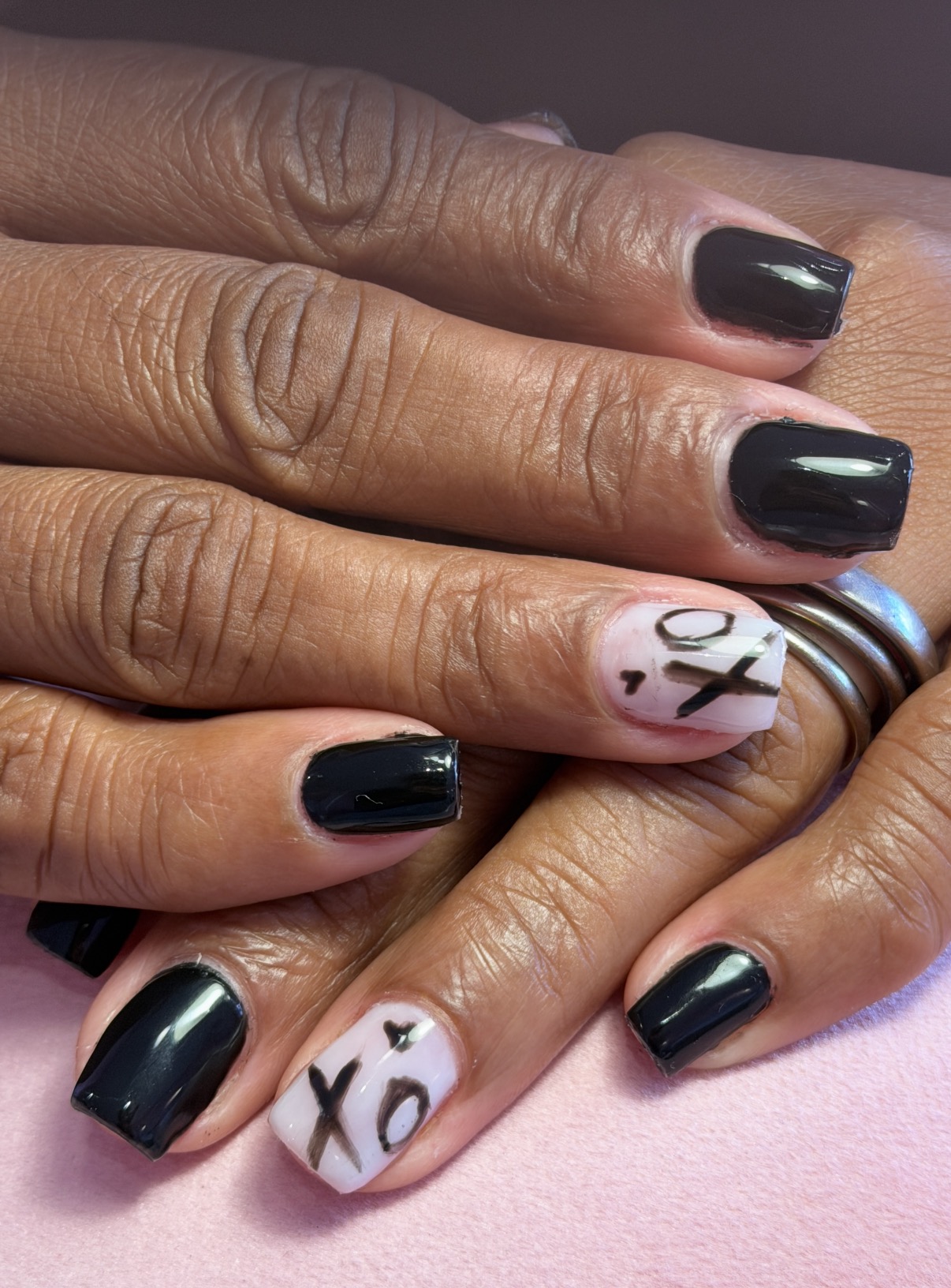 Unhas curtas em verniz de gel preto, com nail art XO a preto sobre base leitosa, feitas no Hit Nails Mafra